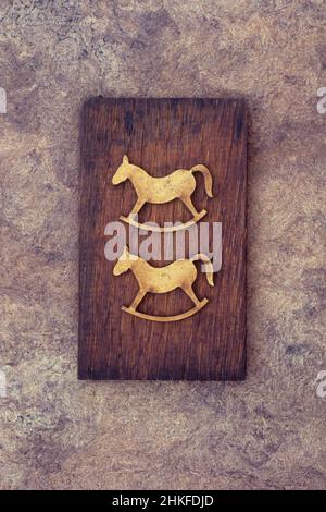 Two flat stained wooden cutouts of rocking horses lying on old wood Stock Photo