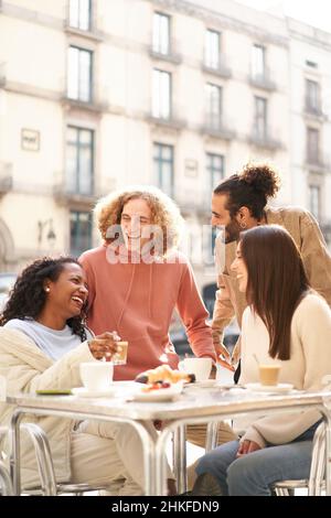Vertical photo of Friends group toasting latte at coffee bar terrace. Group of people talking and having fun together at cappuccino restaurant Stock Photo