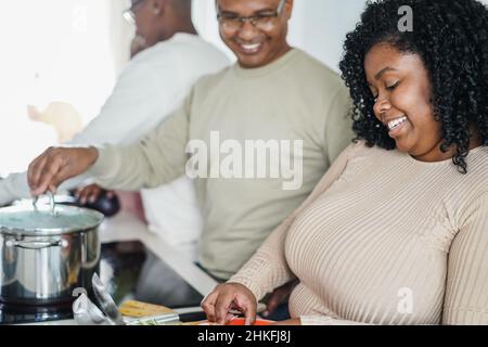 Happy black family cooking inside kitchen at home - Focus on girl face Stock Photo