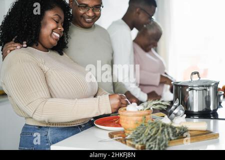 Happy black family cooking inside kitchen at home - Focus on daughter face Stock Photo