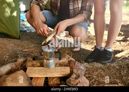 Putting on the morning coffee. Shot of campers preparing a campfire to make coffee. Stock Photo