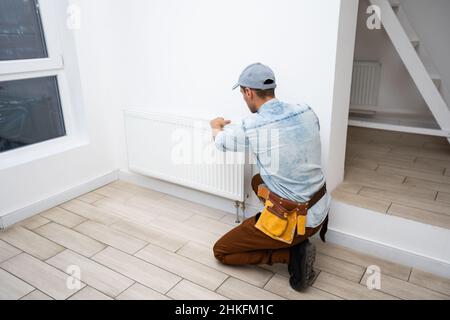 Close-up Of Male Plumber Fixing Thermostat Using Wrench At Home. Stock Photo