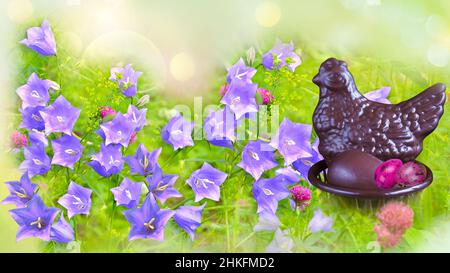 Chocolate Easter chicken with eggs in a basket on a defocused grass background with flowers. Easter Concept Stock Photo