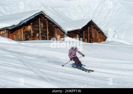 France, Haute Savoie, Mont Blanc massif, Val Montjoie, les Contamines Montjoie, winter activity in the ski area, downhill skiing, skier in front of old chalets on the Montjoie piste Stock Photo