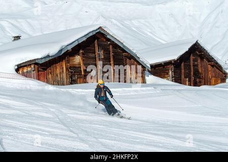 France, Haute Savoie, Mont Blanc massif, Val Montjoie, les Contamines Montjoie, winter activity in the ski area, downhill skiing, skier in front of old chalets on the Montjoie piste Stock Photo