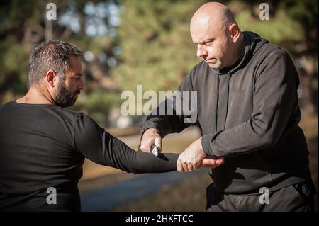 Knife threat. Kapap instructor demonstrates martial arts self defense disarming technique against knife attack. Weapon disarm training. Demonstration Stock Photo