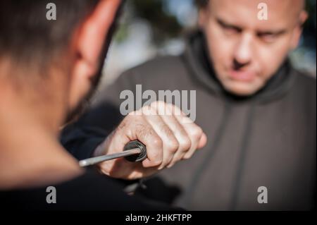 Knife threat. Kapap instructor demonstrates martial arts self defense disarming technique against knife attack. Weapon disarm training. Demonstration Stock Photo