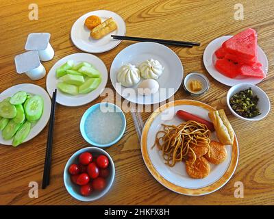 Top view of traditional Chinese breakfast: steamed buns, rice porridge, fried dough sticks, tofu bean curd and pickled veggie. Stock Photo