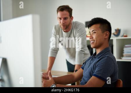 Going over the details. Cropped shot of two designers working together on a project in an office. Stock Photo