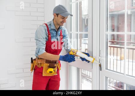 Construction worker putting sealing foam tape on window in house Stock Photo