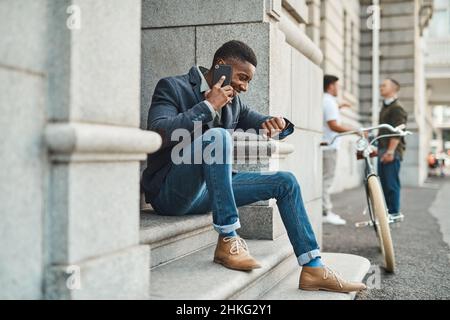No greater business tool than time. Shot of a young businessman using a smartphone and checking the time against an urban background. Stock Photo