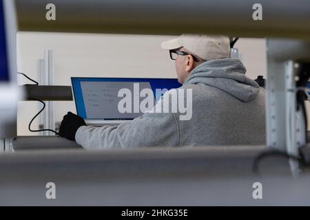 Minsk, Belarus - Jan 05, 2022: Photo of a man in a gray suit checking the computer at work. Testing. Engineer at a modern high-tech factory. Stock Photo