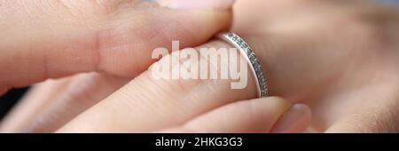 Woman hand putting silver ring on her finger closeup Stock Photo