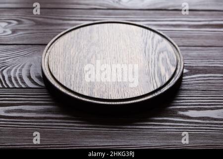 Round cutting board with groove on wooden table background Stock Photo