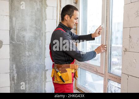 Construction worker repairing windows in house. Stock Photo