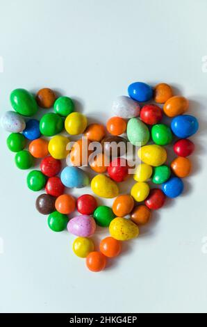 Small multi-colored heart-shaped candies on a white background with space for writing text Stock Photo