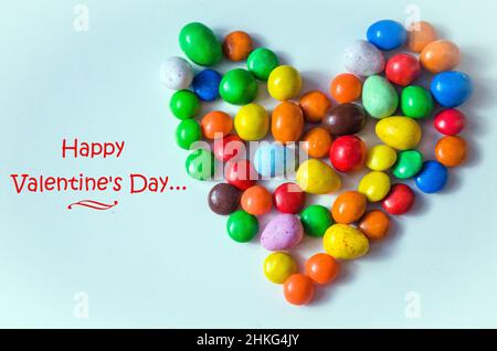 Small multi-colored heart-shaped candies on a white background with space for writing text Stock Photo