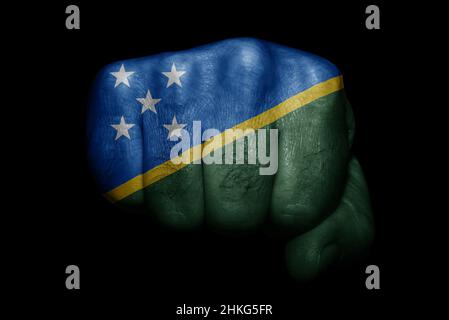 Flag of Solomon Islands painted on strong fist on black background Stock Photo