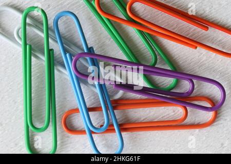 colorful paper clips on white background. A scattered pile of colorful multi-colored metal paper clips (Gem clips) isolated on a white background. Stock Photo