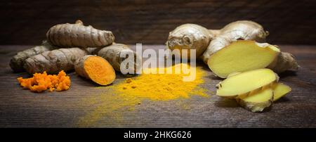 Turmeric and ginger, two Asian spicy roots with healthy effects, dark wooden planks, panoramic format, selected focus, narrow depth of field Stock Photo