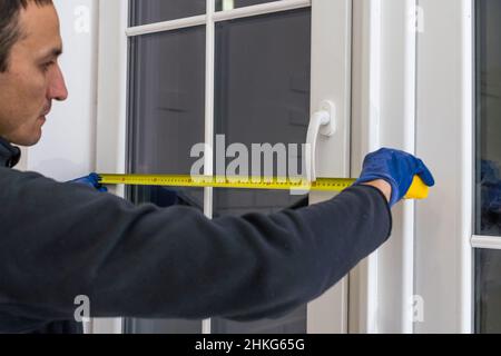 service man installing window with measure tape Stock Photo
