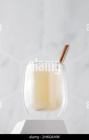 Healthy bone broth in a transparent mug on a pedestal with a spoon on a light background. Stock Photo