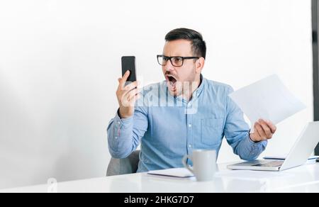 Angry disagreeable businessman sitting at the desk talking online video conference call making unpleasant discussion arguing confronting opinion decis Stock Photo