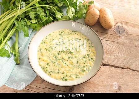 Homemade vegetarian and vegan vegetable soup from parsley leaves and potatoes in a deep dish on a rustic wooden table, copy space, selected focus, nar Stock Photo