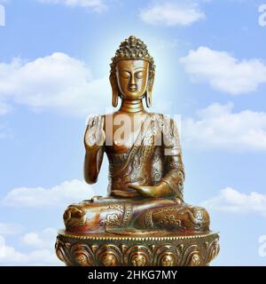 Figure of sitting Buddha and the blue sky with clouds in the  background Stock Photo