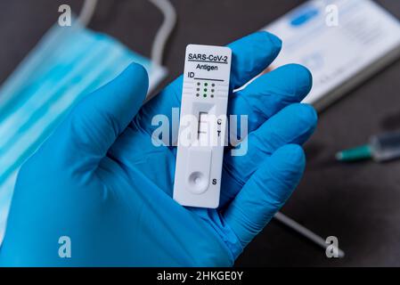 A hand wearing a protective glove is seen holding a rapid Covid test, also known as antigen test or lateral flow test, showing a positive result in a Stock Photo