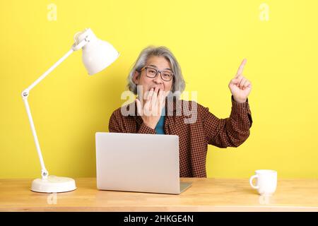 The senior Asian man working on laptop with color background. Stock Photo