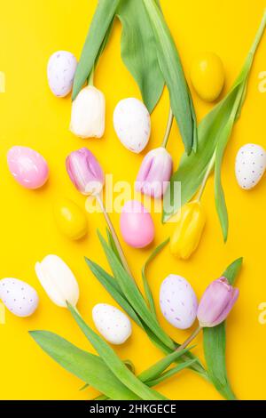 Easter greeting card. Multicolored easter eggs and tulips on yellow background. Easter concept Stock Photo