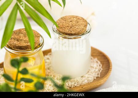 Fermented beauty care. Wellness composition with hande made rice water, green tea water, lemon water and cosmetic accessories on a white table. Natura Stock Photo