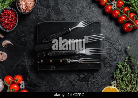 Rustic Cutting Board and meat fork on Dark wooden board. Black background. Top view. Copy space Stock Photo