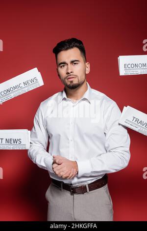 bearded businessman in white shirt near newspapers on red Stock Photo