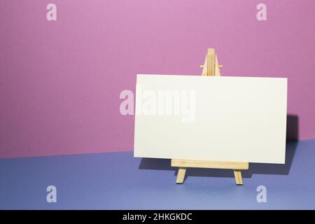 Easel with blank canvas on blue desk. purple wall background. copy space Stock Photo
