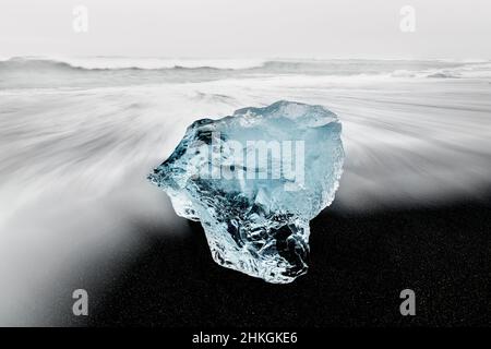 Blue ice chunk in the rolling waves of famous Diamond Beach. Stock Photo