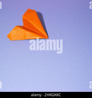 Orange paper airplane on blue background. copy space Stock Photo