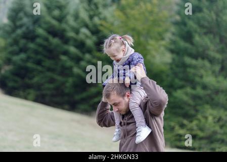 Father and daughter enjoying a piggyback ride at park Stock Photo