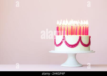 Birthday cake with lots of pink birthday candles on a pink background Stock Photo