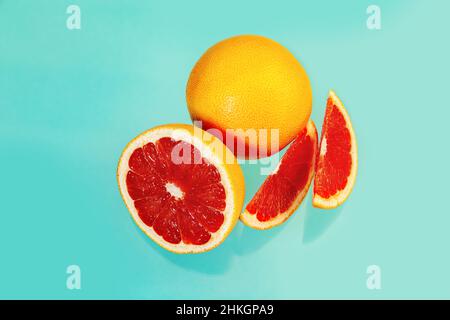 Whole and sliced juicy grapefruits on a light blue background. Food background. Stock Photo