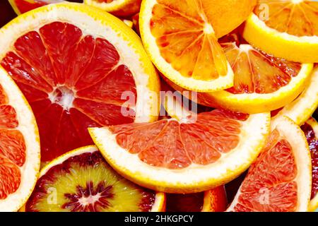 Whole and sliced juicy red oranges and grapefruits on a blue background. Wallpaper, food background. Stock Photo