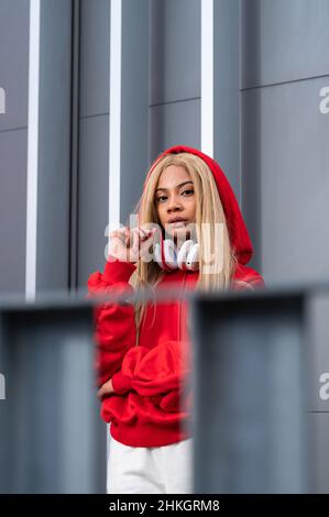Cheerful African American woman with long blonde hair wearing sportswear and wearing headphones Stock Photo