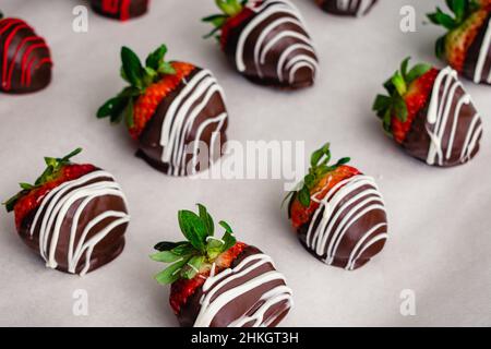 Making Chocolate Covered Strawberries and Pineberries: Freshly made candied berries on a parchment paper lined sheet pan Stock Photo