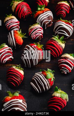 Closeup View of Chocolate Covered Strawberries and Pineberries: Candied berries on a dark wood background Stock Photo