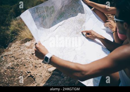 Couple exploring map while sitting on hill Stock Photo