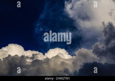 Vivid, uniquely-framed cloudscape in a conflicted sky of overlapping blues, whites and greys. Stock Photo