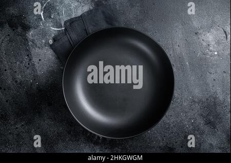 Empty black craft plate on table. Table setting. Black background. Top view. Copy space Stock Photo