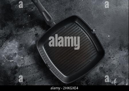 Empty cast-iron grill pan for cooking on rustic towel. Black background. Top view. Copy space Stock Photo