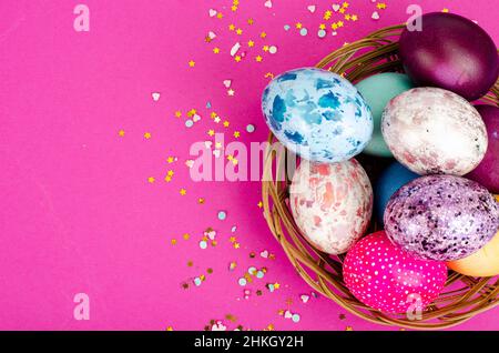 Multicolored handmade easter eggs and confetti on pink background. Minimal concept. View from above. Space for text. Photo Stock Photo